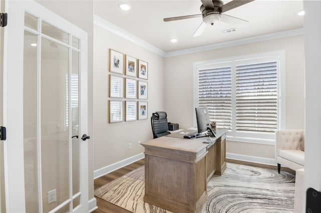 office space with visible vents, baseboards, ceiling fan, light wood-type flooring, and ornamental molding