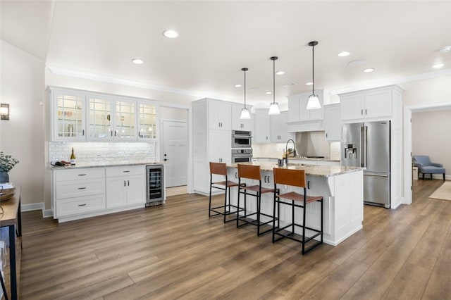 kitchen featuring dark wood finished floors, stainless steel appliances, wine cooler, white cabinets, and a kitchen breakfast bar