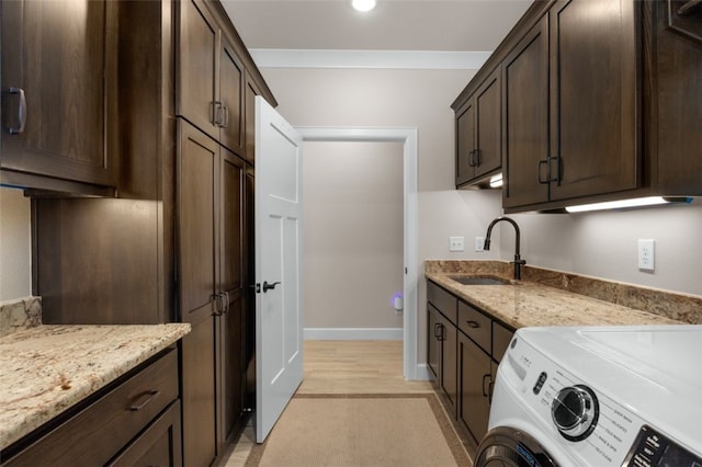 kitchen with a sink, light stone counters, washer / clothes dryer, and dark brown cabinets