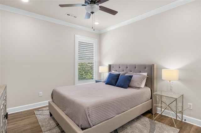 bedroom featuring visible vents, wood finished floors, baseboards, and ornamental molding