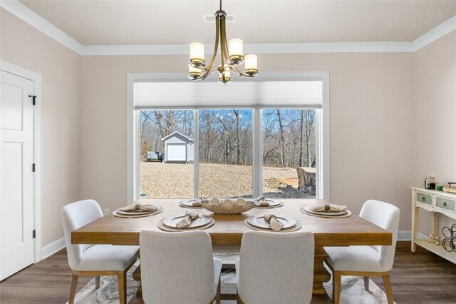 dining room featuring dark wood finished floors, a notable chandelier, baseboards, and ornamental molding