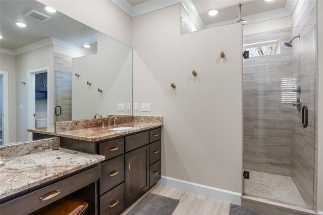 bathroom with visible vents, a stall shower, crown molding, baseboards, and vanity