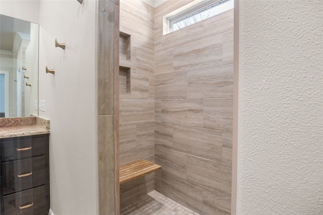 bathroom featuring tiled shower, vanity, and a textured wall