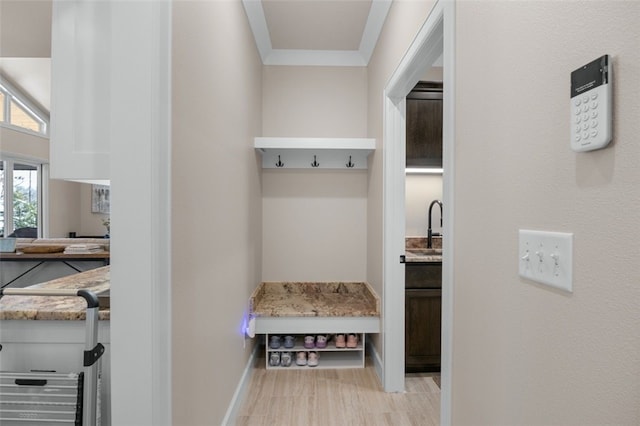 mudroom featuring crown molding, light wood-type flooring, baseboards, and a sink