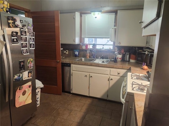 kitchen with tile counters, backsplash, stainless steel appliances, and a sink