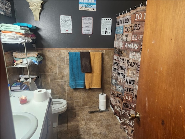 full bathroom featuring visible vents, toilet, tile walls, and vanity