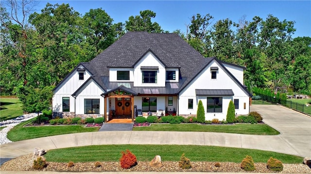 modern inspired farmhouse with a standing seam roof, fence, a front yard, a shingled roof, and metal roof