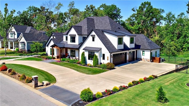 modern farmhouse with a front yard, fence, roof with shingles, a standing seam roof, and metal roof