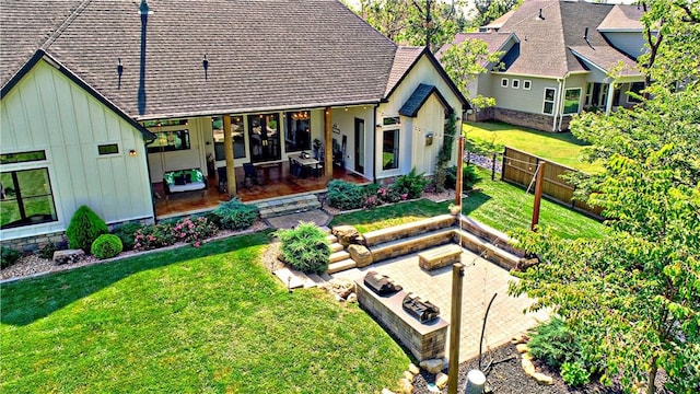 rear view of house with a lawn, board and batten siding, a shingled roof, and an outdoor fire pit