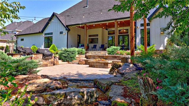 rear view of house featuring a patio area, roof with shingles, and an outdoor fire pit