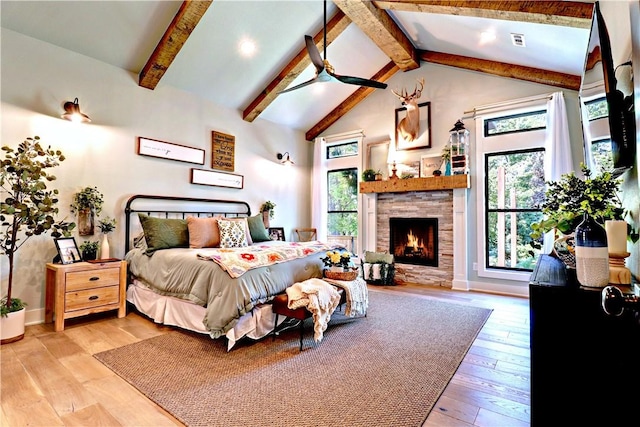 bedroom with visible vents, beam ceiling, a fireplace, wood finished floors, and high vaulted ceiling