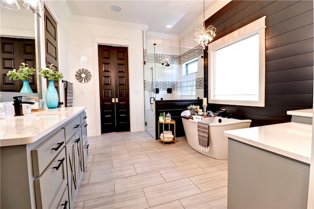 bathroom with a chandelier, a freestanding bath, a stall shower, and vanity