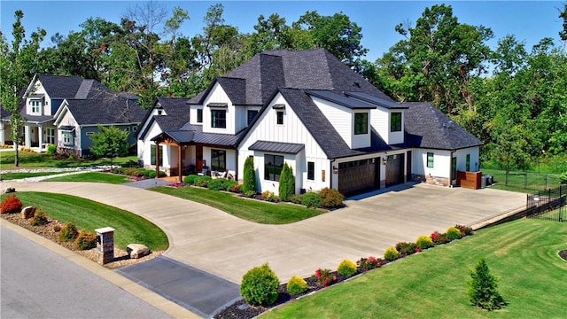 modern inspired farmhouse with board and batten siding, a shingled roof, a front lawn, fence, and metal roof