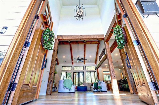 foyer featuring beam ceiling, ornamental molding, wood finished floors, and high vaulted ceiling