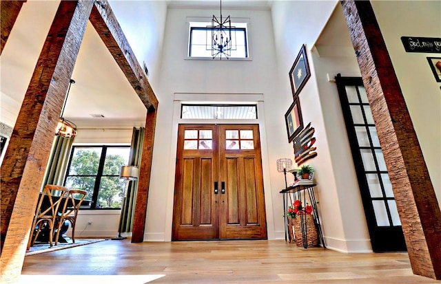 foyer entrance with baseboards, a high ceiling, an inviting chandelier, and wood finished floors