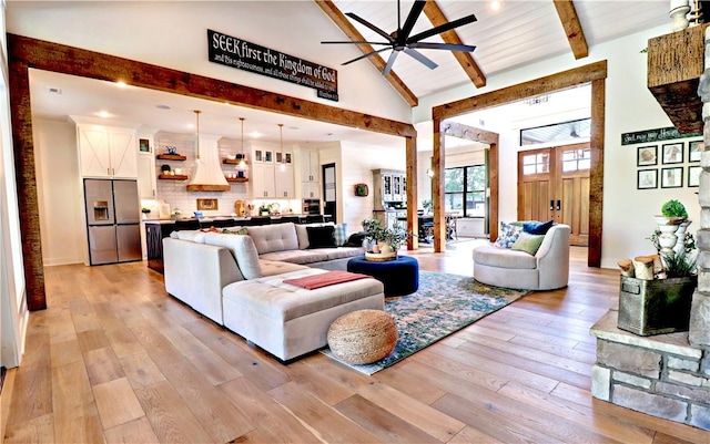 living area with light wood finished floors, beamed ceiling, high vaulted ceiling, and ceiling fan