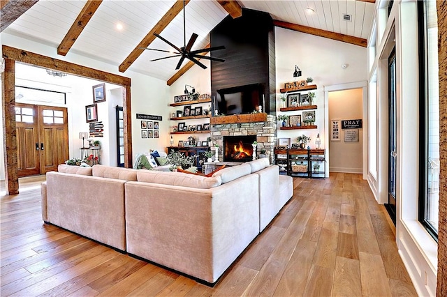 living area with light wood finished floors, high vaulted ceiling, beam ceiling, a fireplace, and wood ceiling