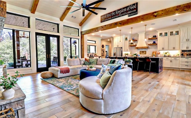 living room featuring beam ceiling, plenty of natural light, french doors, and light wood-type flooring