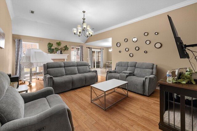 living area featuring visible vents, light wood-style floors, an inviting chandelier, and ornamental molding