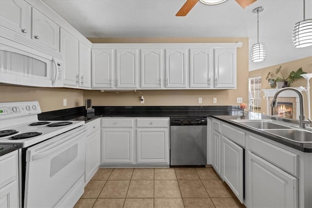 kitchen with white appliances, light tile patterned flooring, a sink, white cabinetry, and dark countertops