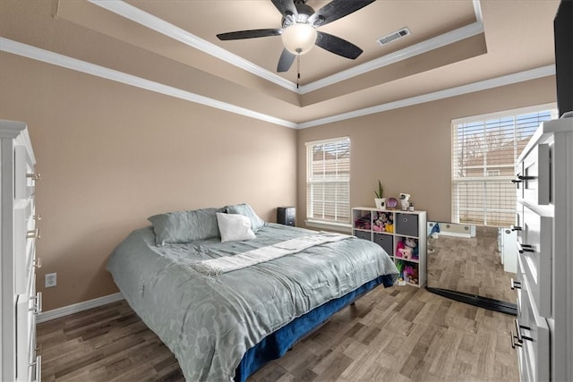 bedroom featuring visible vents, crown molding, a raised ceiling, and wood finished floors