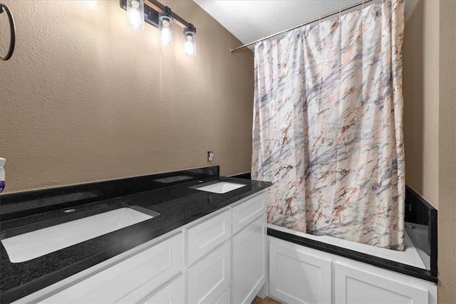 bathroom with double vanity, a textured wall, shower / bath combo with shower curtain, and a sink