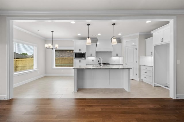 1804 Charles St, Pea Ridge, AR 72751 - kitchen with stainless steel microwave, custom range hood, white cabinetry, backsplash, and a chandelier