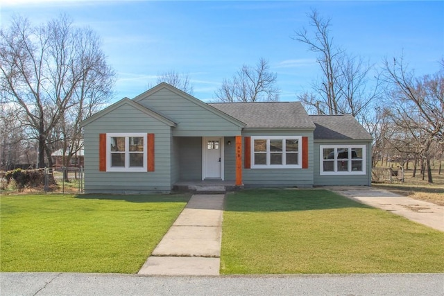 view of front facade featuring a shingled roof, a front yard, and fence