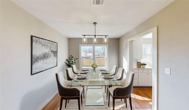 dining space with wood finished floors, visible vents, and baseboards