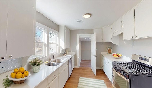 kitchen with visible vents, a sink, appliances with stainless steel finishes, white cabinets, and light countertops