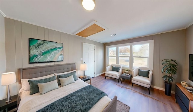 bedroom featuring visible vents, wood finished floors, crown molding, baseboards, and attic access