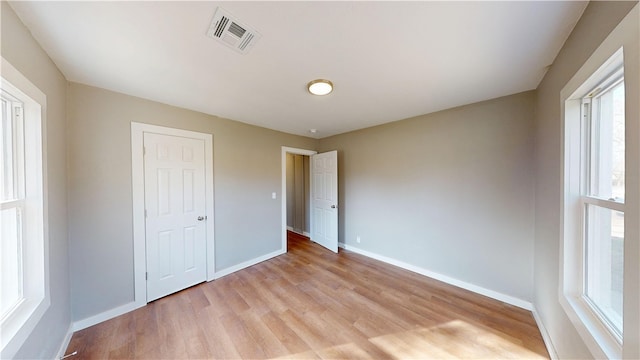 unfurnished bedroom with visible vents, baseboards, and light wood-style floors