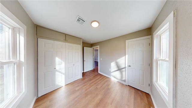 unfurnished bedroom with light wood-style floors, visible vents, a closet, and baseboards