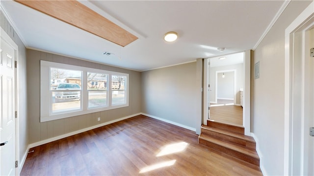 unfurnished room featuring visible vents, crown molding, baseboards, and wood finished floors