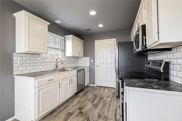 kitchen featuring visible vents, a sink, white cabinets, light wood-style floors, and appliances with stainless steel finishes