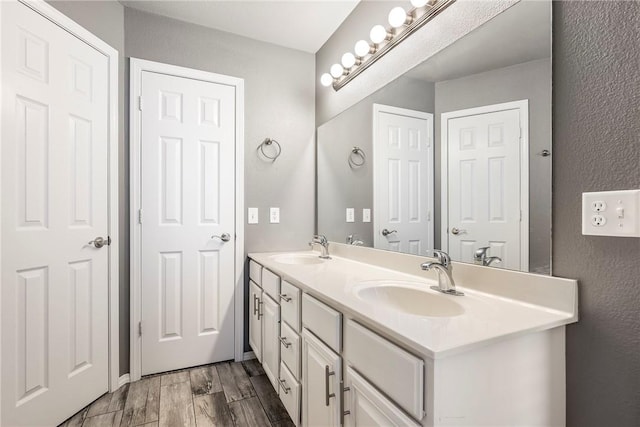 full bath with a sink, wood finish floors, and double vanity