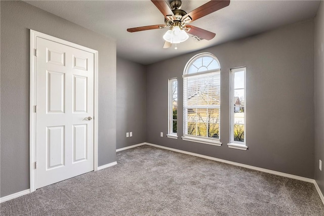 unfurnished room featuring visible vents, baseboards, carpet floors, and ceiling fan