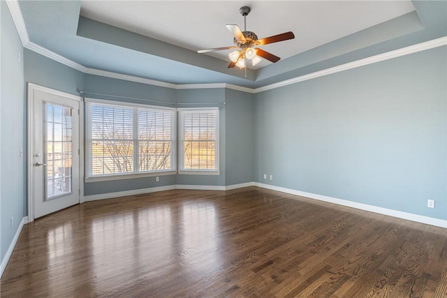 empty room featuring baseboards, a raised ceiling, dark wood-style floors, and a ceiling fan