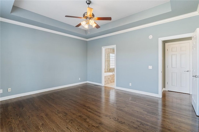 spare room with baseboards, a ceiling fan, a tray ceiling, and wood finished floors