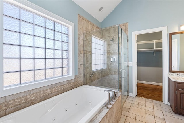 full bathroom featuring vanity, a stall shower, a whirlpool tub, vaulted ceiling, and a spacious closet