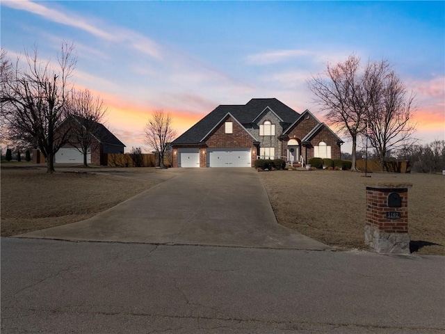 french country style house featuring stone siding, driveway, and a garage