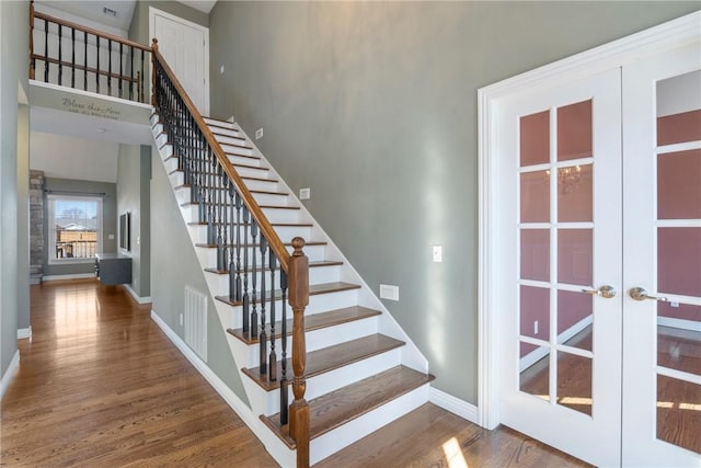 stairway featuring wood finished floors, french doors, visible vents, and baseboards