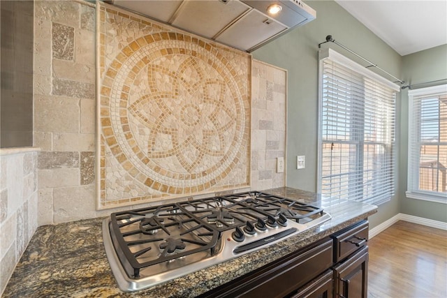 kitchen featuring wood finished floors, dark brown cabinetry, stainless steel gas stovetop, extractor fan, and backsplash