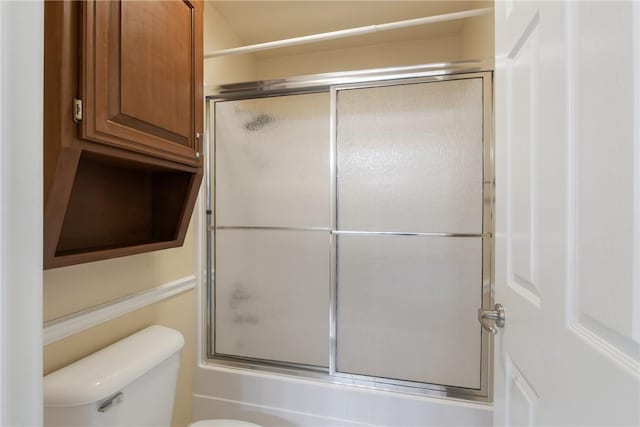 bathroom with toilet and bath / shower combo with glass door