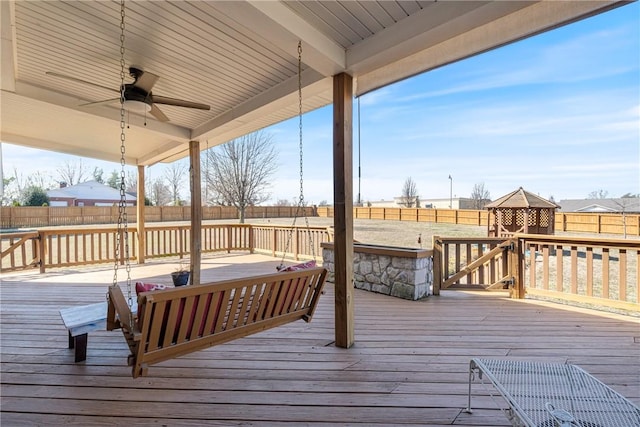 wooden terrace with a ceiling fan and a fenced backyard