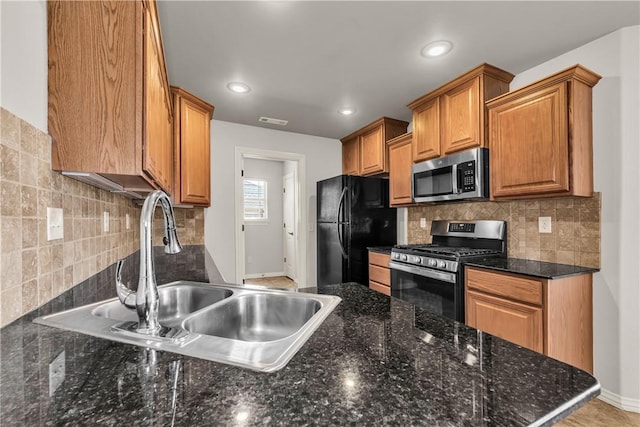 kitchen featuring visible vents, a sink, stainless steel appliances, tasteful backsplash, and brown cabinets