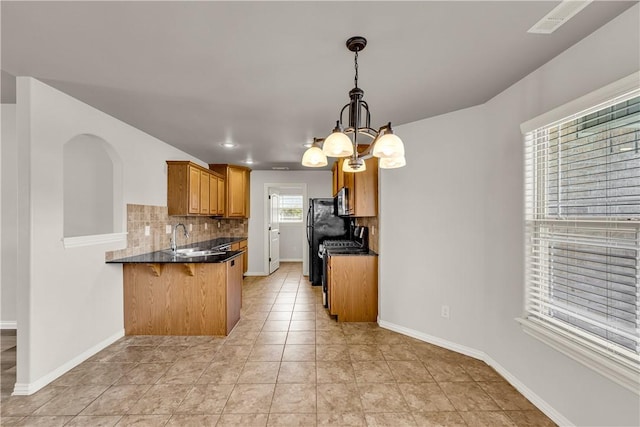 kitchen featuring dark countertops, range, a peninsula, and a sink