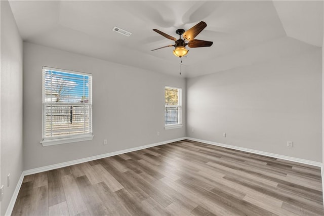 unfurnished room featuring ceiling fan, wood finished floors, visible vents, and baseboards