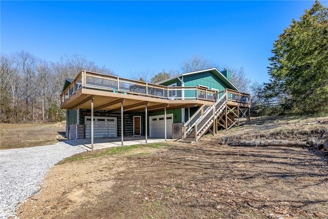 view of front of property featuring stairs, a garage, driveway, and a wooden deck