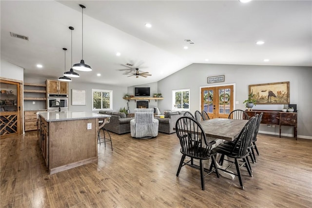 dining area featuring visible vents, lofted ceiling, a healthy amount of sunlight, and wood finished floors